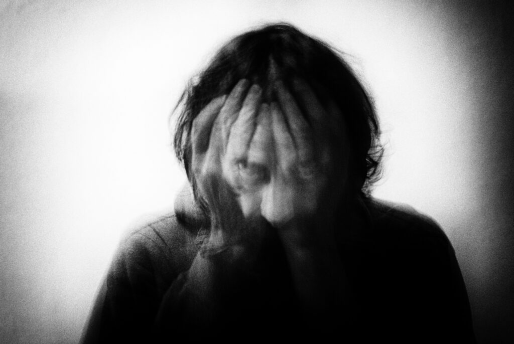 woman covering her face in her hands, representing the reality of battling your own emotions